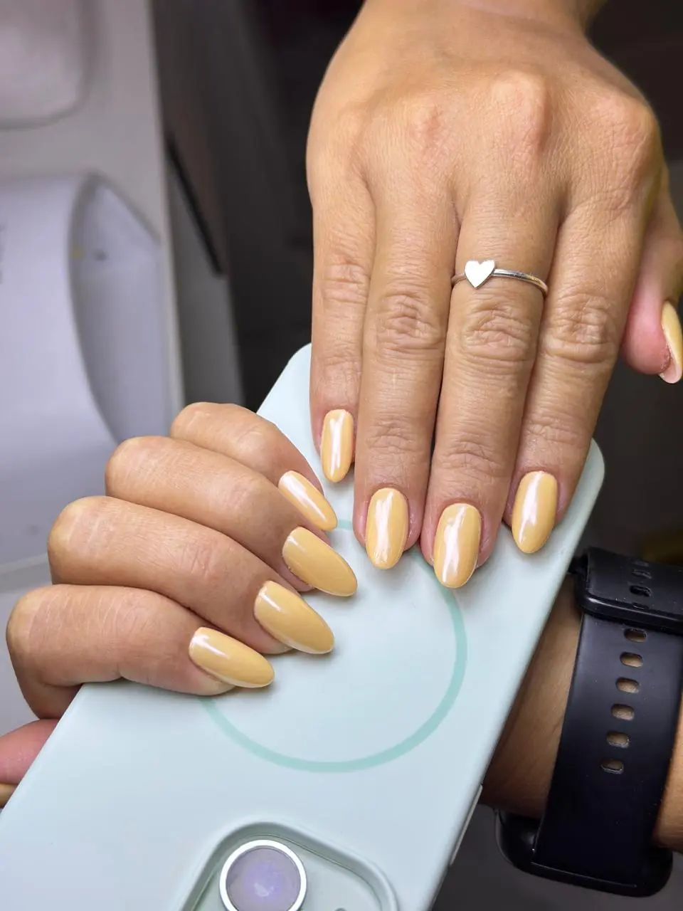 Unhas amendoadas com esmaltação amarela de acabamento brilhante