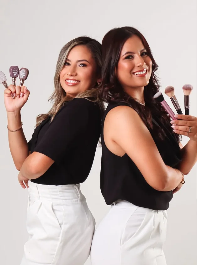 Beatriz e Karoline juntas, segurando produtos de unhas e maquiagem